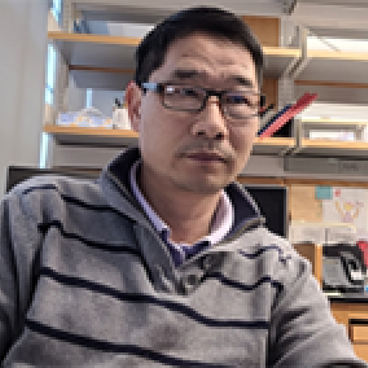 Gong Wu in the lab wearing a striped shirt